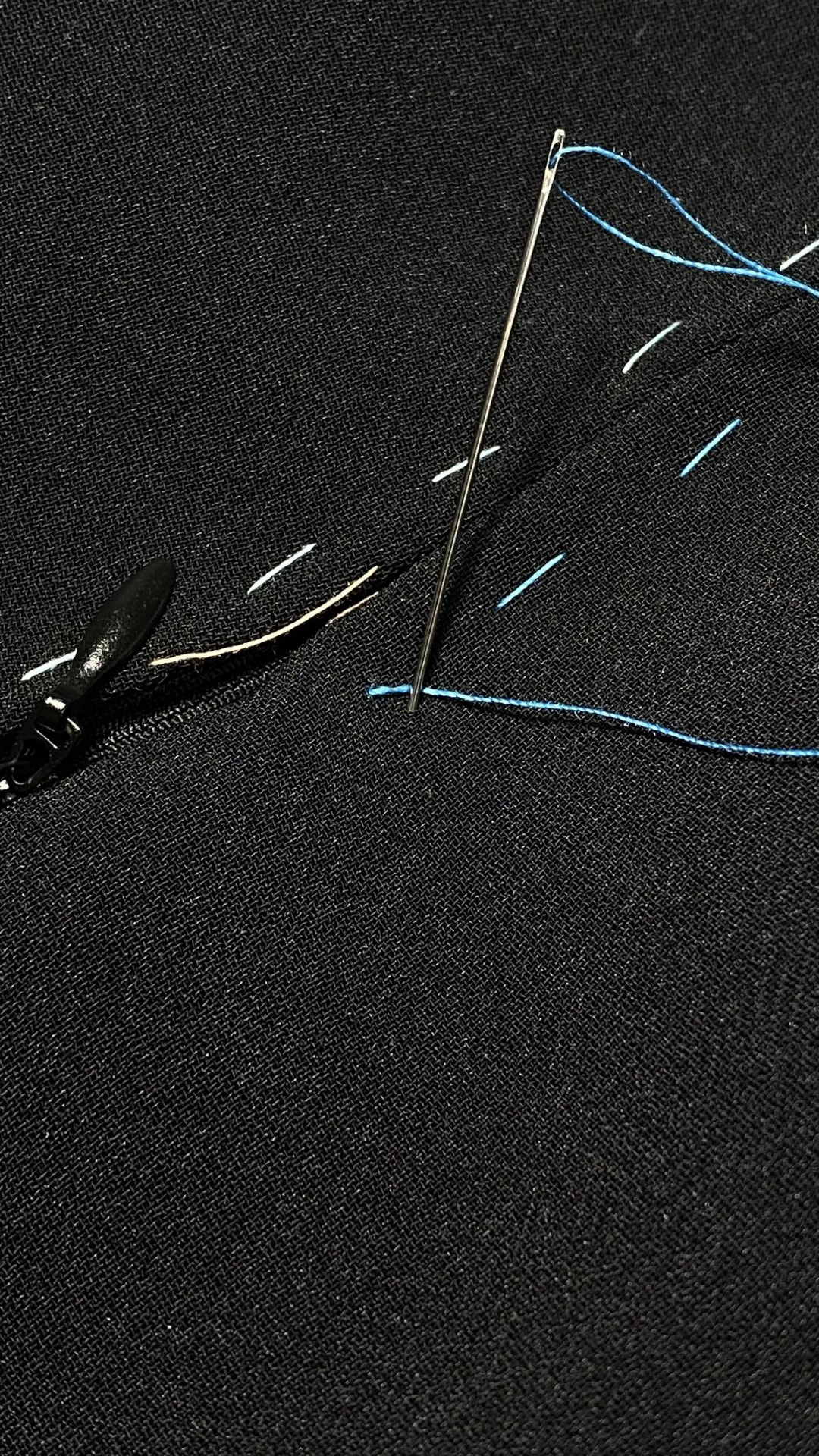 Tailoring chalk lines and a needle on dark cloth